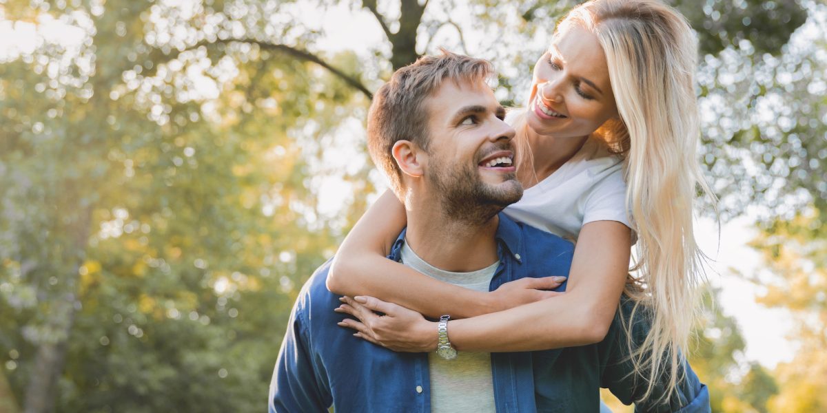 low-angle-view-of-young-beautiful-couple-piggybacking-and-having-fun-outdoors-.jpg